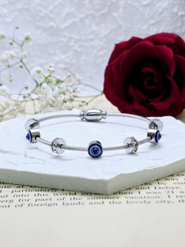 Stylish silver-tone cable bracelet featuring "Evil Eye" and sparkling bead accents.