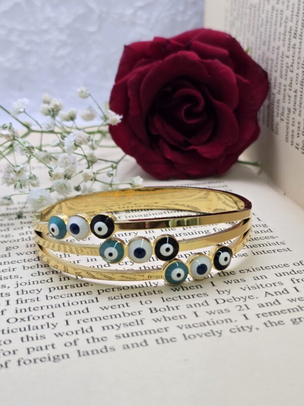 Stylish gold-tone bangle featuring protective "Evil Eye" beads.